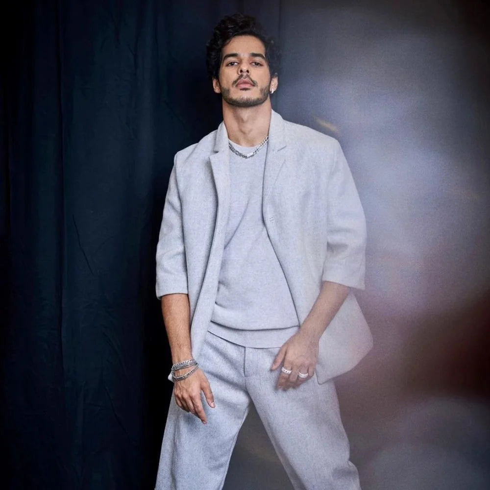 Ishaan Khatter in Orionz Jewels wearing a light gray suit against a dark background