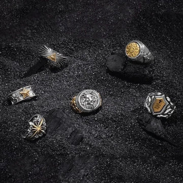 Collection of silver rings with various designs on a dark surface