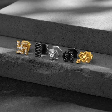 Five pairs of earrings in different designs on a textured surface