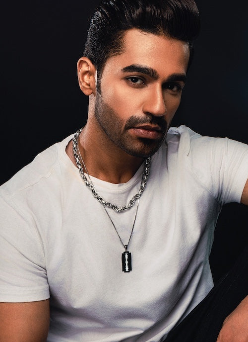 Man wearing a white t-shirt and orionz chain necklace against a dark background