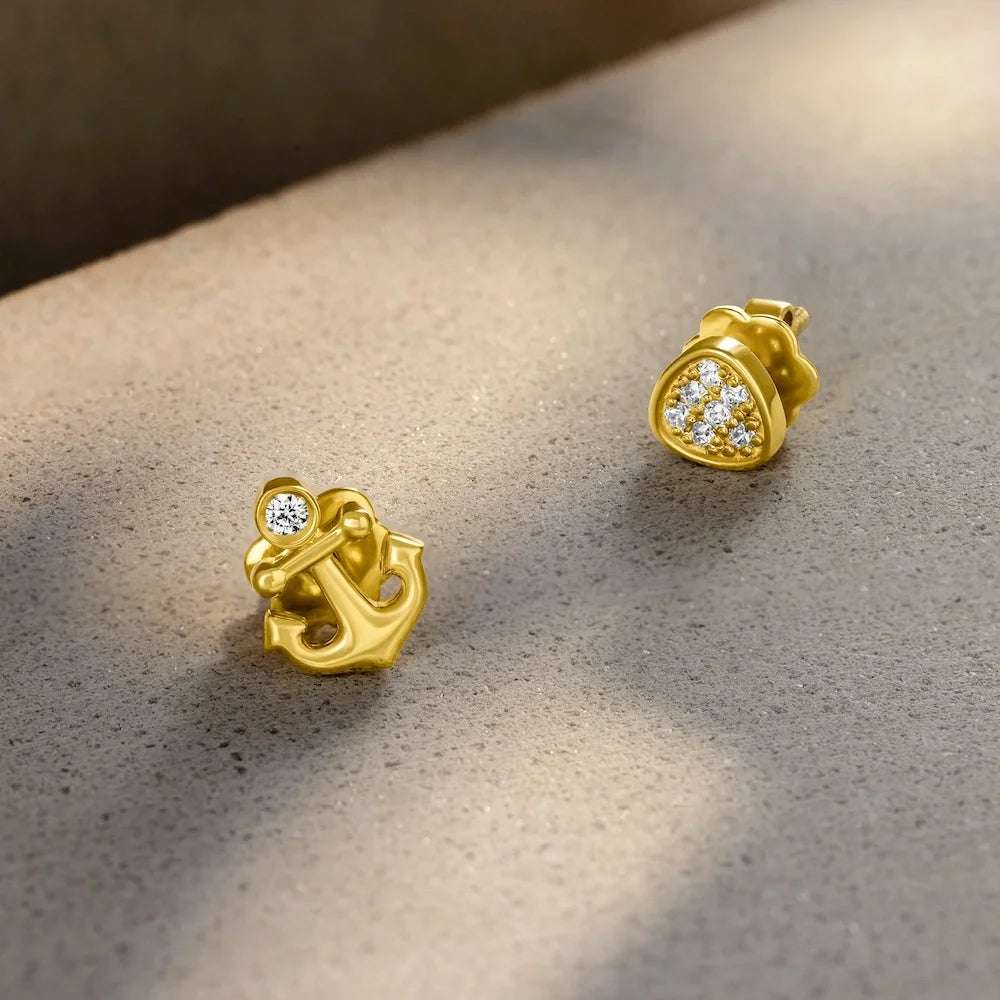 orionz Gold anchor-shaped earrings with diamond accents on a textured surface