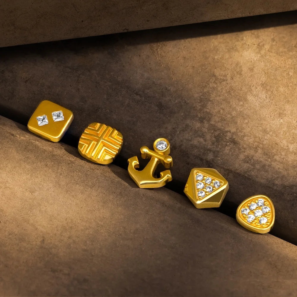 Set of orionz gold errings with various designs on a brown surface