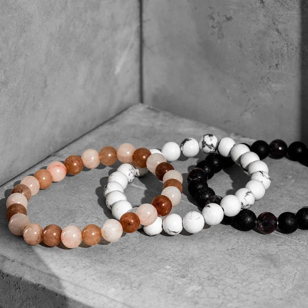 orionz three beaded bracelets in brown, white, and black on a concrete surface.