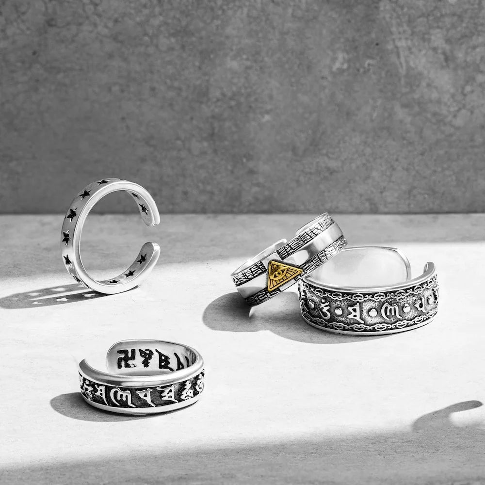 Set of orionz silver rings with intricate designs on a light surface with a gray background
