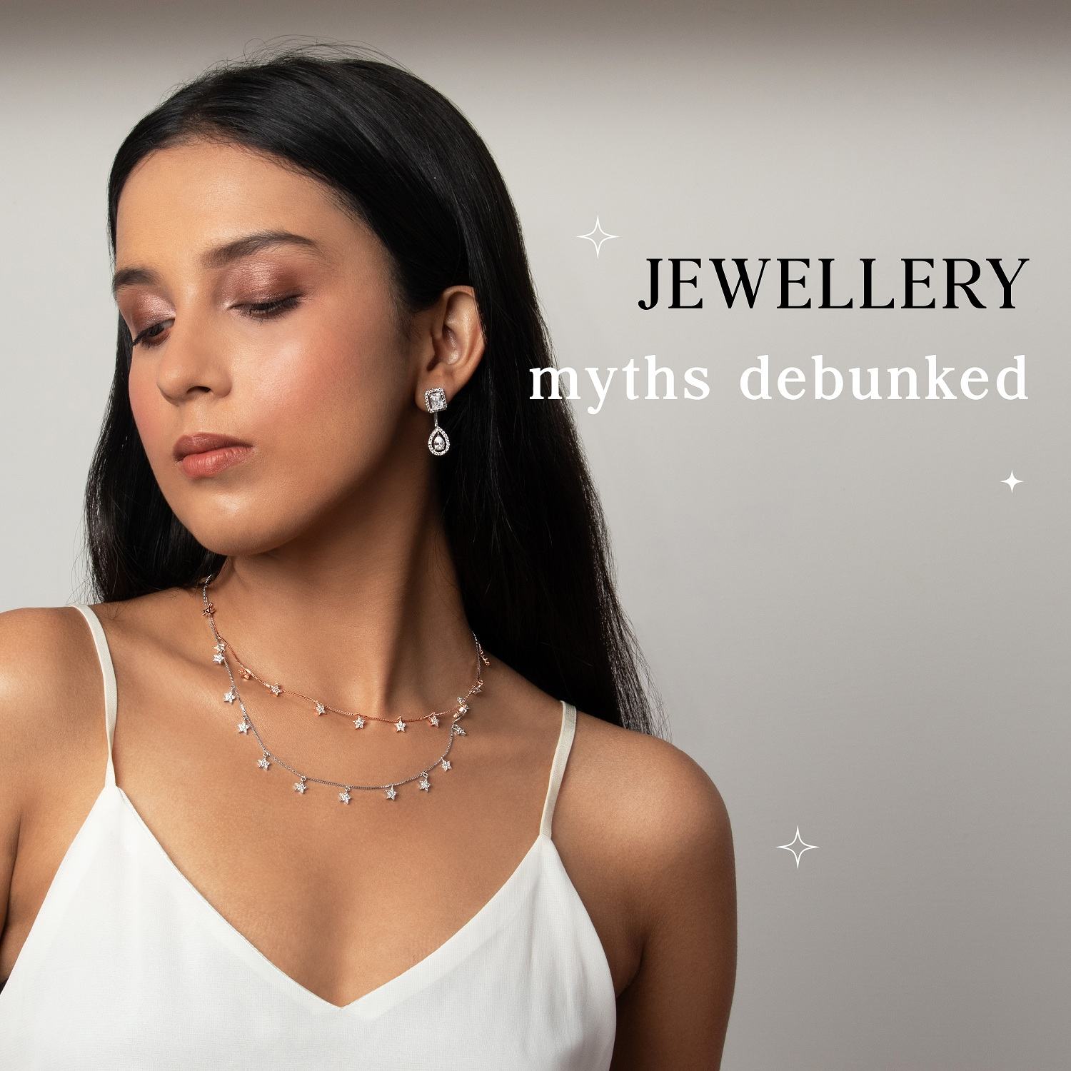 Elegant jewelry worn by a woman with dark hair, featuring sparkling earrings, layered necklaces, and a white satin dress, highlighting jewelry myths debunked.