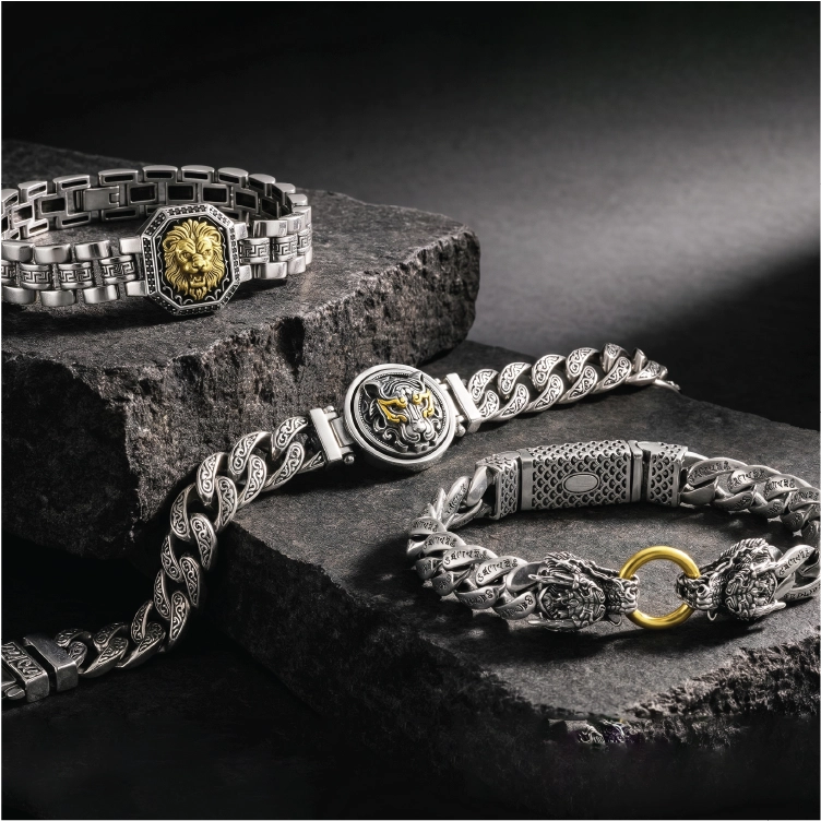 Three silver bracelets with gold accents on a dark surface