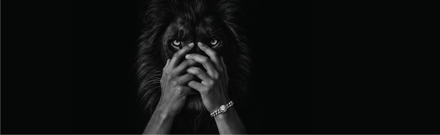 A dramatic black and white portrait of a lion with a person's hands covering its face, set against a solid black background.