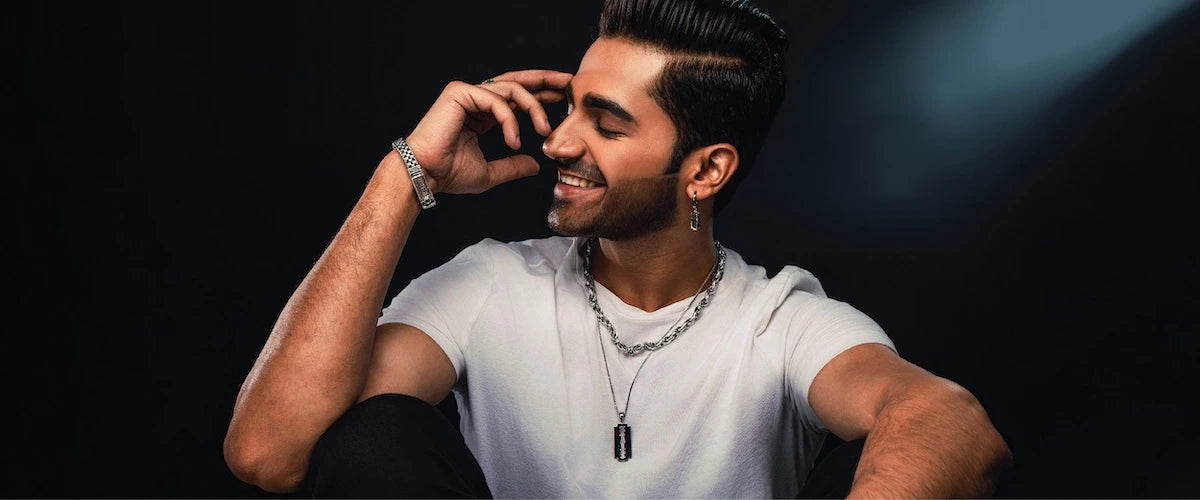 Man in a white t-shirt with orionz jewellery on a dark background