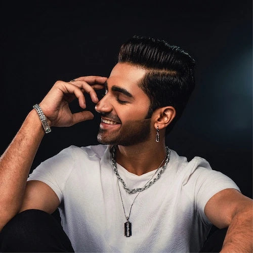Man wearing a white shirt with orionz jewellery against a dark background