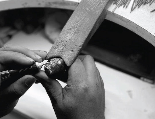 Person using a tool on a small object with a blurred background