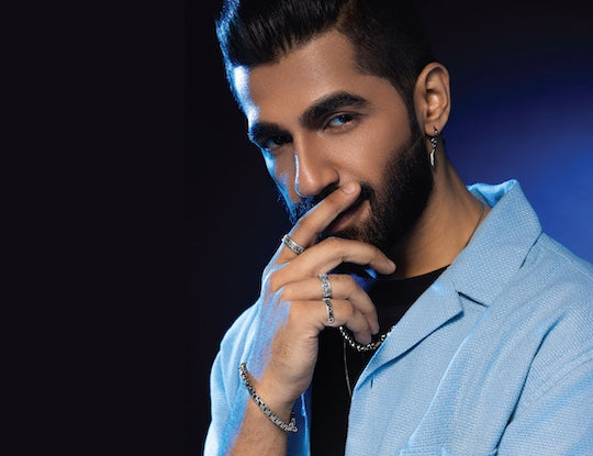 Man in a light blue shirt with orionz jewellery on a dark background