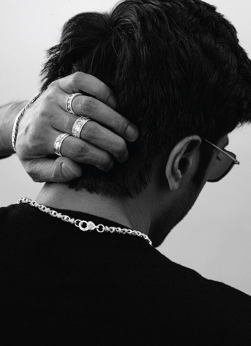 Person wearing multiple orionz rings and a necklace with a neutral background