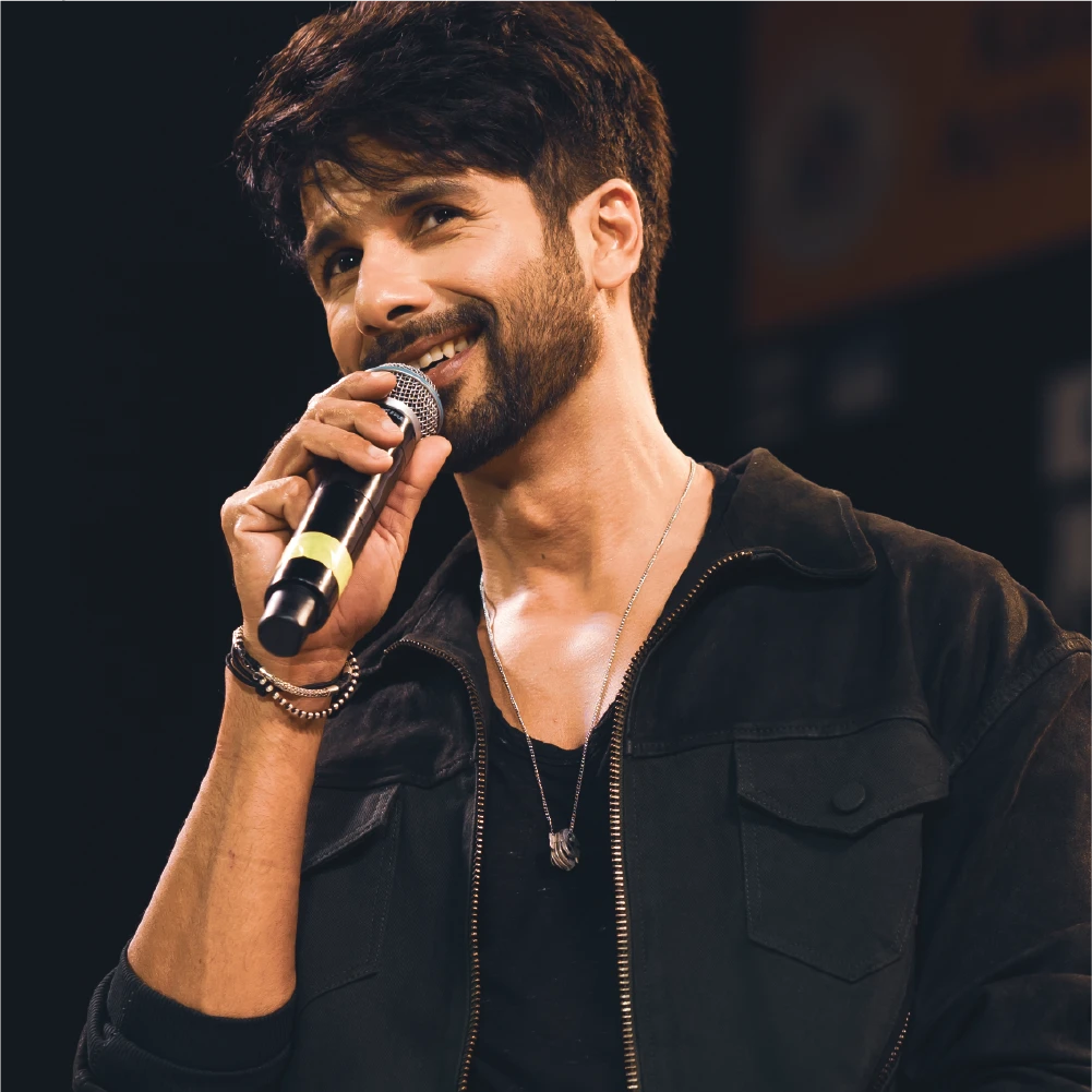 Man holding a microphone on stage with a dark background