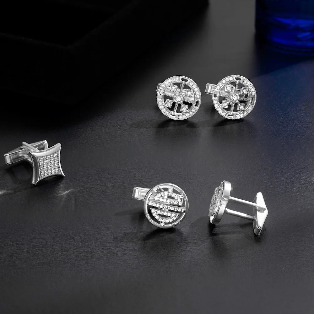 Set of silver cufflinks with intricate designs on a dark surface