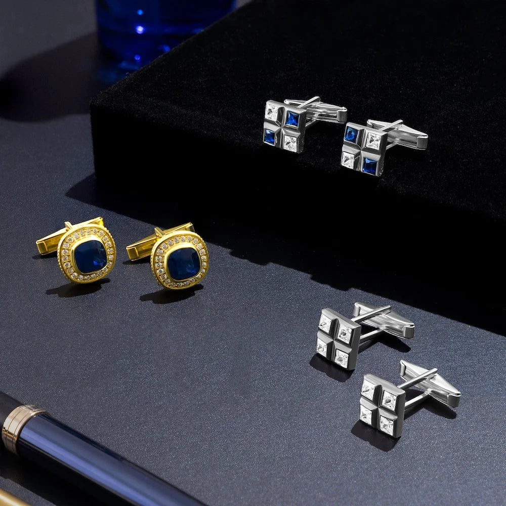 Gold and silver cufflinks with blue stones on a dark surface