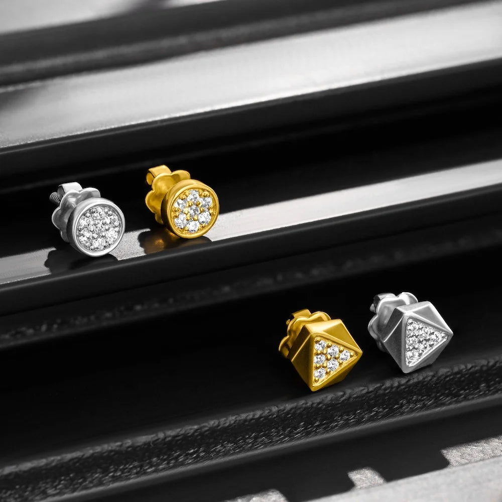 orionz Pair of gold and silver stud earrings on a metallic surface
