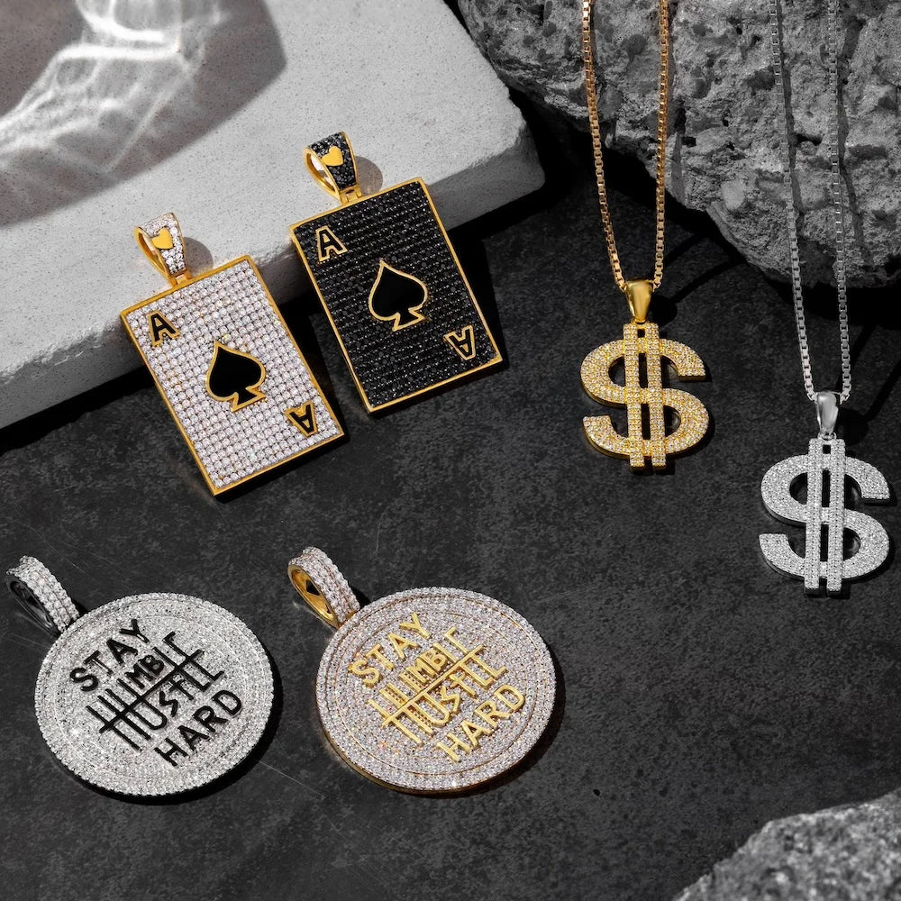 Collection of orionz pendants including playing card suits, dollar signs, and motivational phrases on a dark surface.