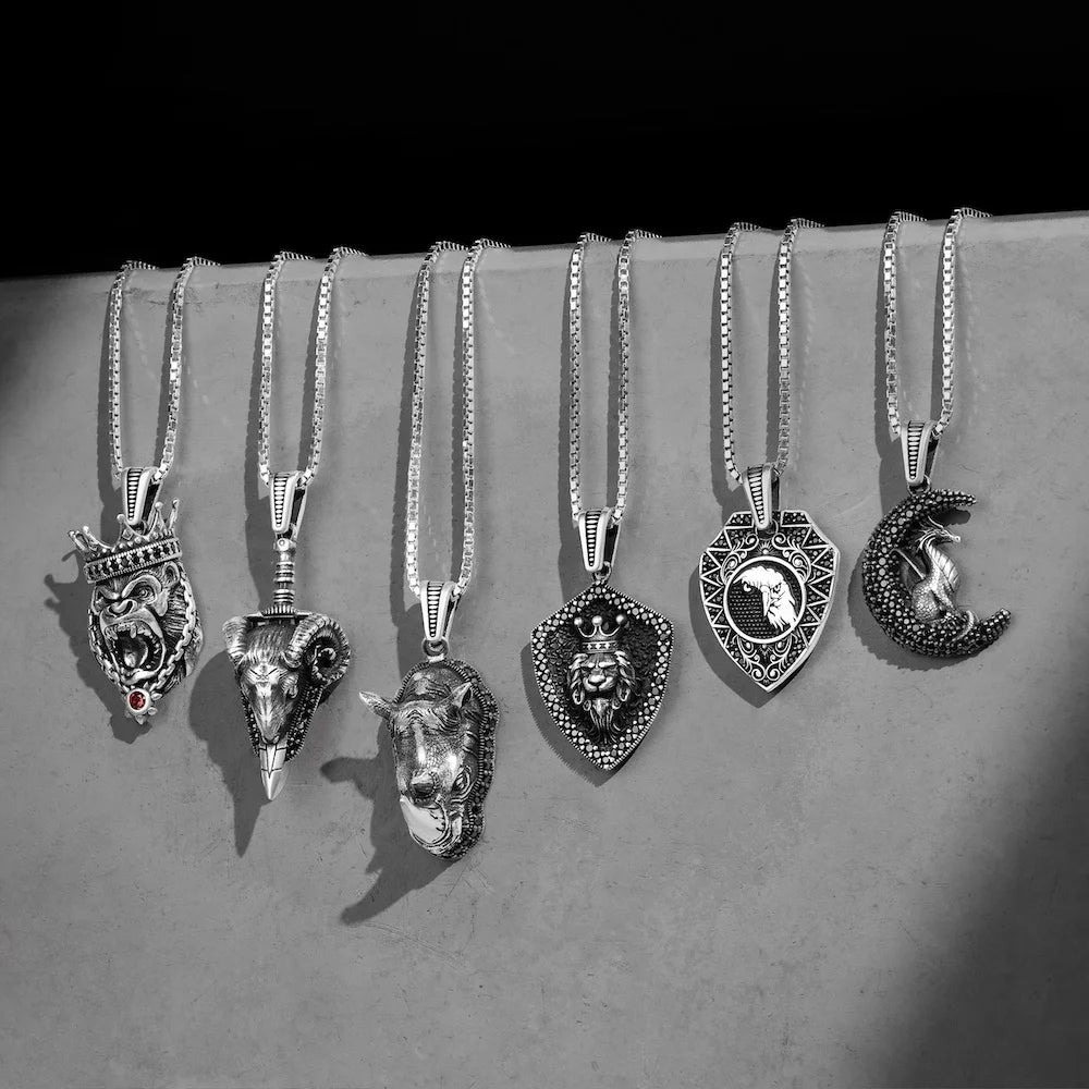 Collection of orionz silver necklaces with various pendants on a gray surface.