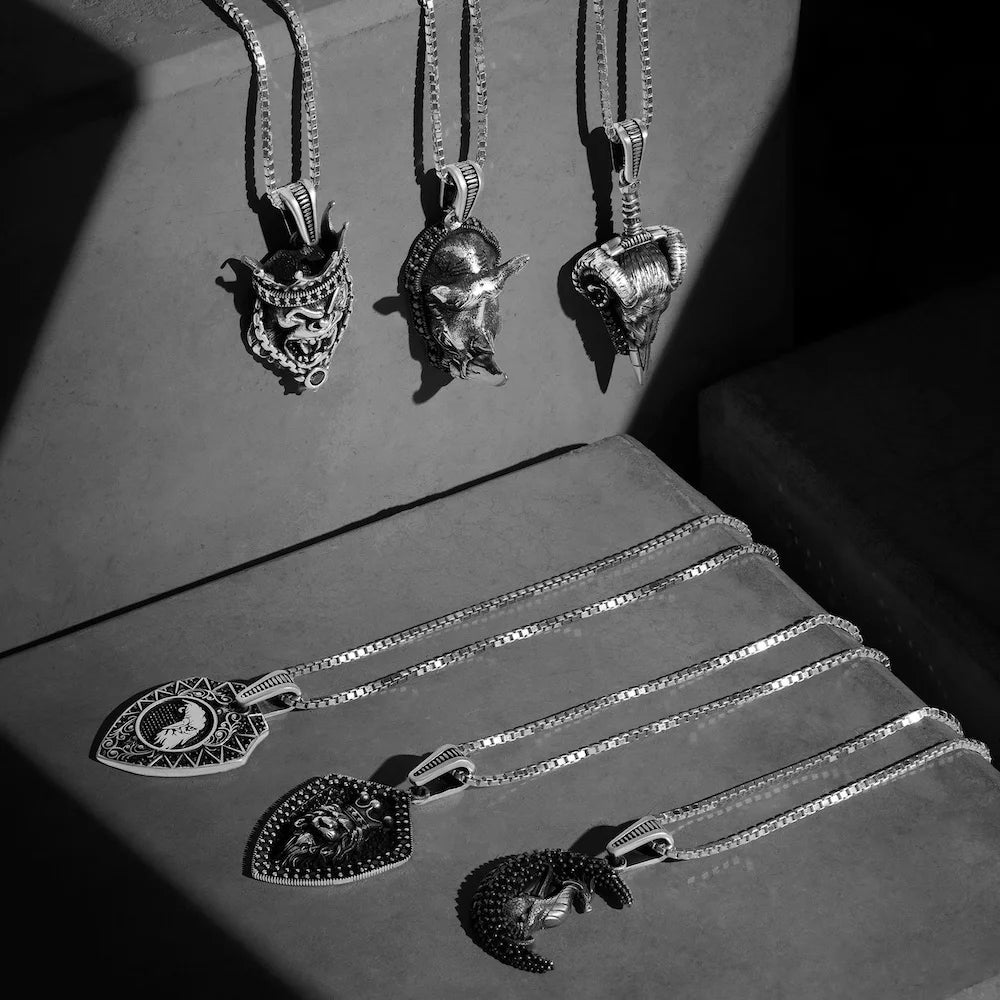 Collection of orionz silver necklaces with unique pendants on a textured surface